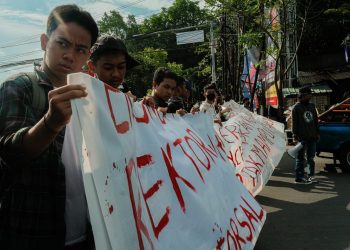 Peserta aksi memegang spanduk yang bertuliskan 'Rektor Pelit' di depan Pintu Satu Unhas, Selasa (2/5). Sumber: IDENTITAS/Agif