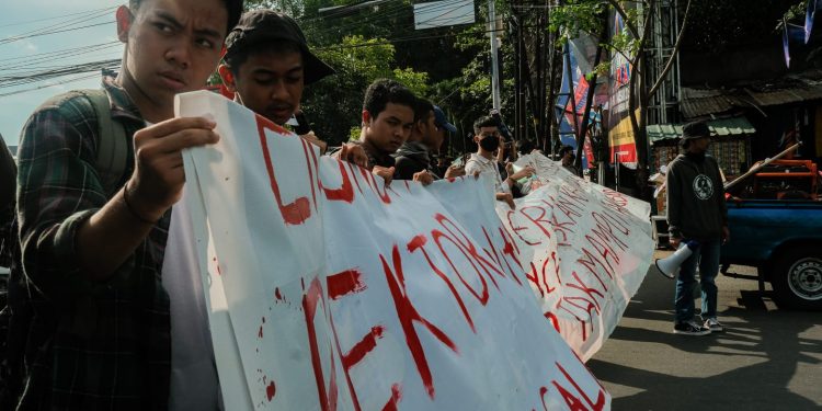 Peserta aksi memegang spanduk yang bertuliskan 'Rektor Pelit' di depan Pintu Satu Unhas, Selasa (2/5). Sumber: IDENTITAS/Agif