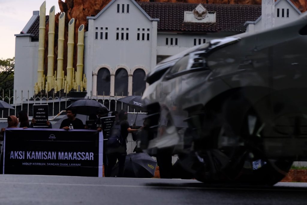 Dari Jauh, para kerumunan aksi masih tetap bertahan di bawah terpaan air hujan.