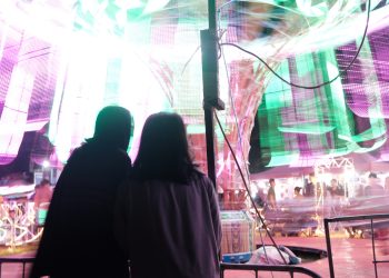 Nampak dua orang pengunjung pasar malam sedang melihat komedi putar, Kamis (02/05).