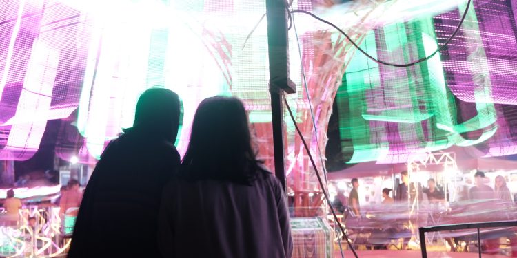 Nampak dua orang pengunjung pasar malam sedang melihat komedi putar, Kamis (02/05).