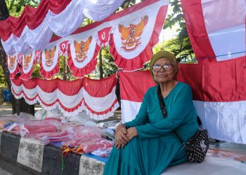 Potrait Daeng Enang dengan latar dagangan benderanya.