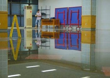 Tampak seseorang sedang menguras air yang menggenangi Lantai Dasar Rektorat Unhas, Rabu (02/10). Foto: IDENTITAS/Adrian.