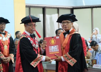 Prof Tasrifin Tahara (kanan) menerima kode etik anggota Dewan Professor usai dikukuhkan sebagai Guru Besar FISIP Unhas di Ruang Senat Gedung Rektorat Unhas, Selasa (18/02). Foto: IDENTITAS/Afifah Khairunnisa