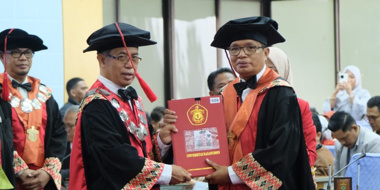 Prof Tasrifin Tahara (kanan) menerima kode etik anggota Dewan Professor usai dikukuhkan sebagai Guru Besar FISIP Unhas di Ruang Senat Gedung Rektorat Unhas, Selasa (18/02). Foto: IDENTITAS/Afifah Khairunnisa