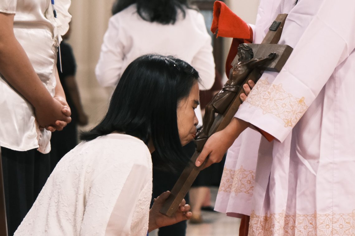 Umat memberi penghormatan kepada salib dengan mencium patung Yesus pada bagian kaki yang dipegang oleh Misdinar
