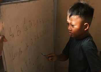 Seorang anak sedang belajar mengidentifikasi alfabet di papan tulis