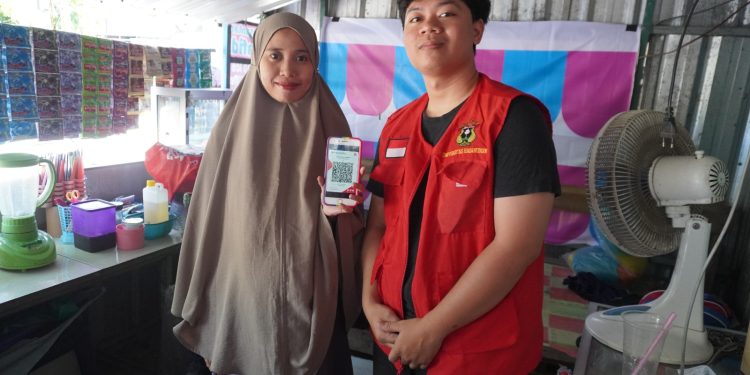 Foto bersama Mahasiswa KKNT Unhas dengan salah satu pedagang di Kelurahan Pangkajene, Kabupaten Sidrap dalam sosialisasi pembayaran QRIS, Selasa (26/7). Foto: Dokumentasi Pribadi