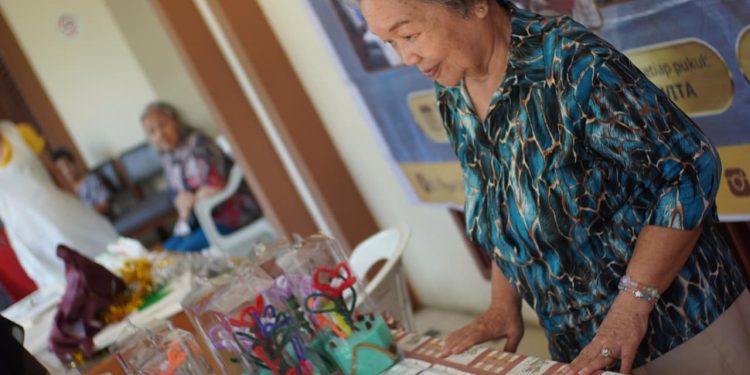 Seorang Lansia yang kerap disapa Oma sedang menjaga tenant pada Pameran Seni Ruang Kreasi Lansia, Minggu (21/9). Foto: Dokumentasi Pribadi