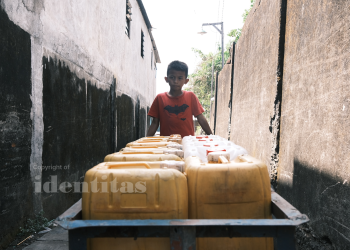 Anak kecil yang mendorong gerobak juga jerikennya untuk membeli air bersih