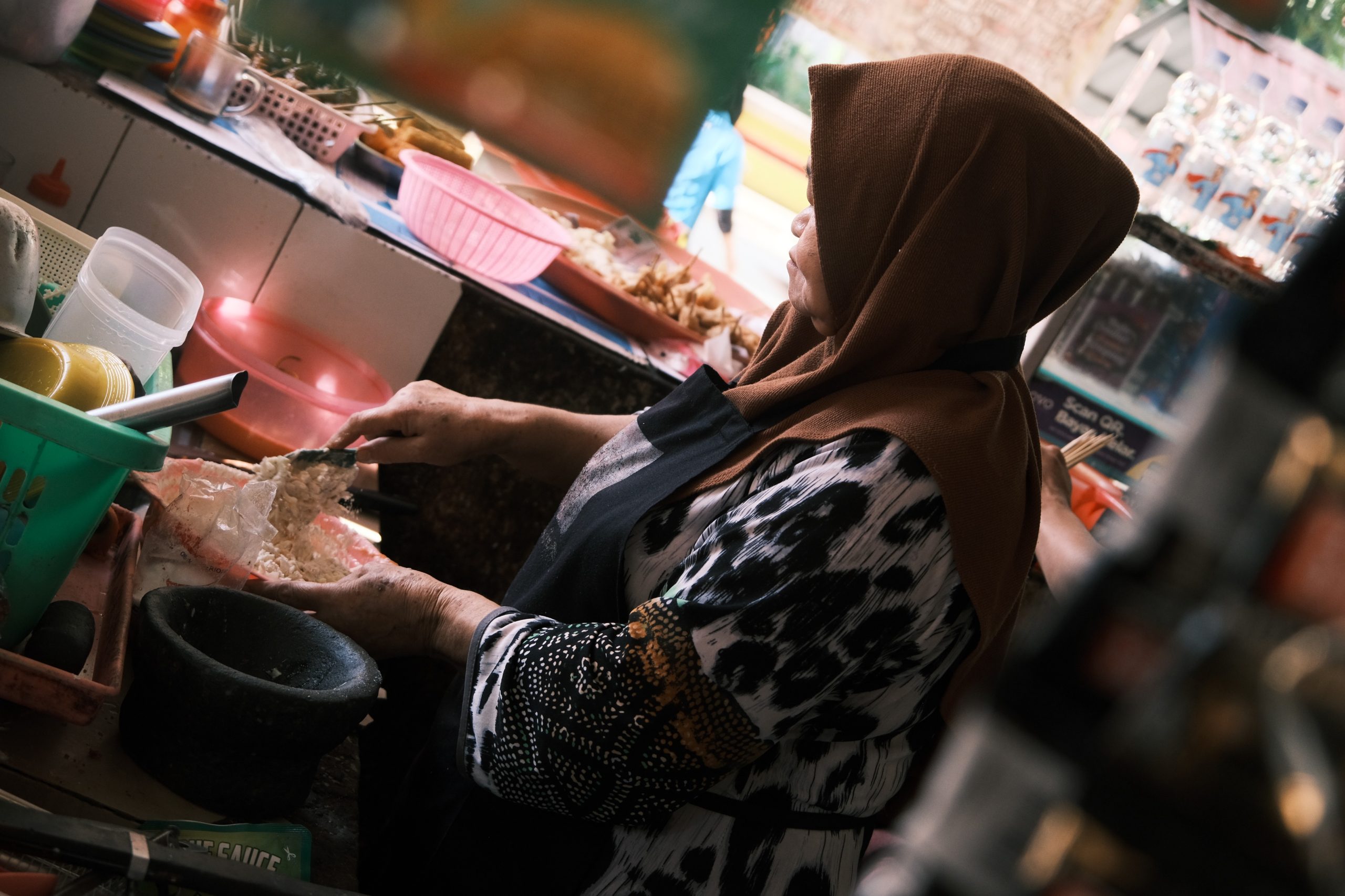 Mace Indah (ibu kantin) yang sedang mengaduk tepung untuk membuat bakwan